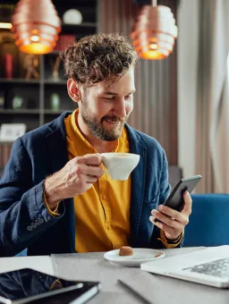 Wattn Smilende mann med kaffekopp og mobil 266691269