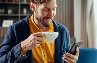 Wattn Smilende mann med kaffekopp og mobil 266691269