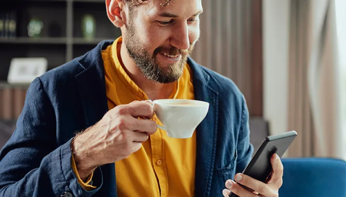 Wattn Smilende mann med kaffekopp og mobil 266691269